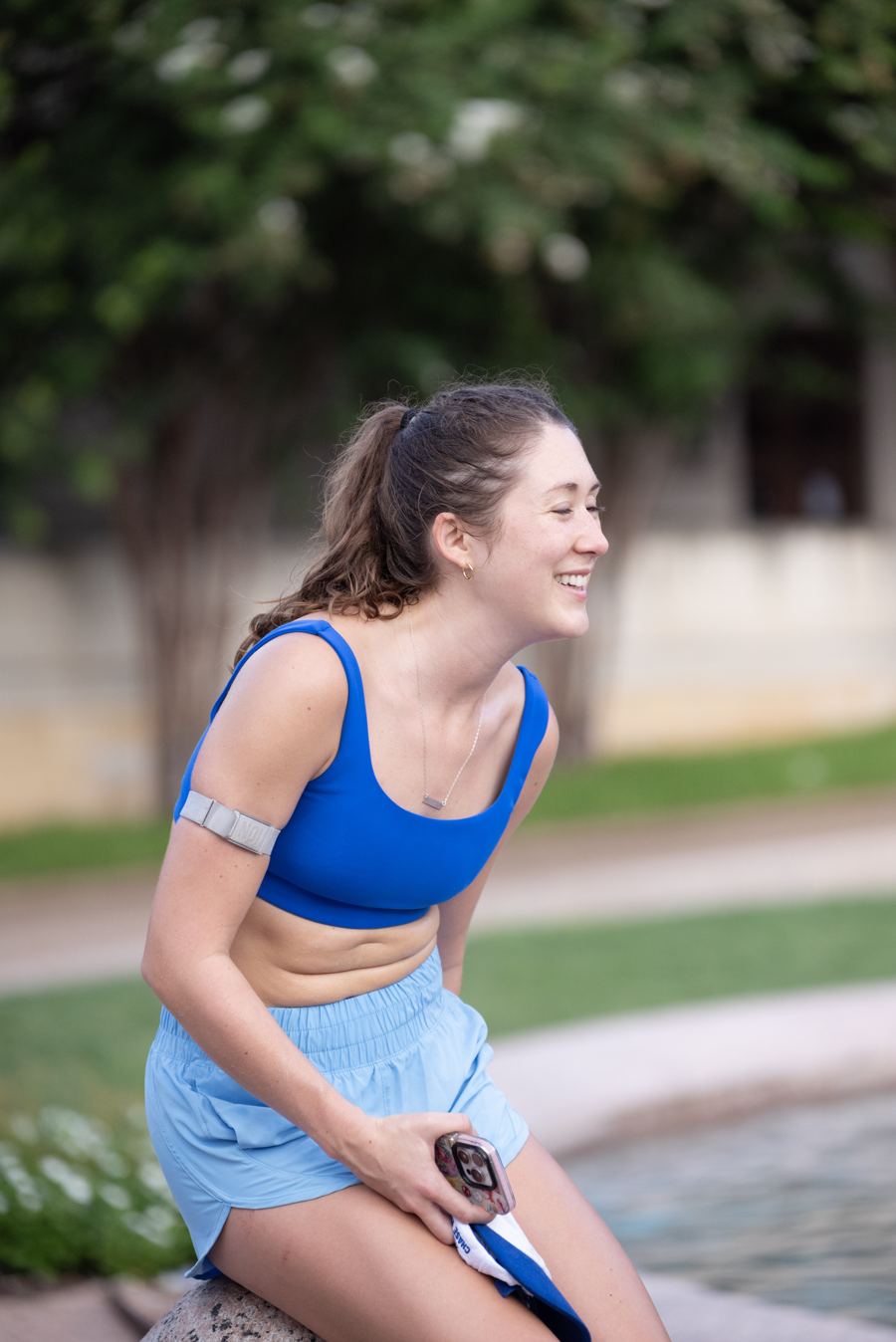 A runner laughing while seated at the edge of Littlefield Fountain
